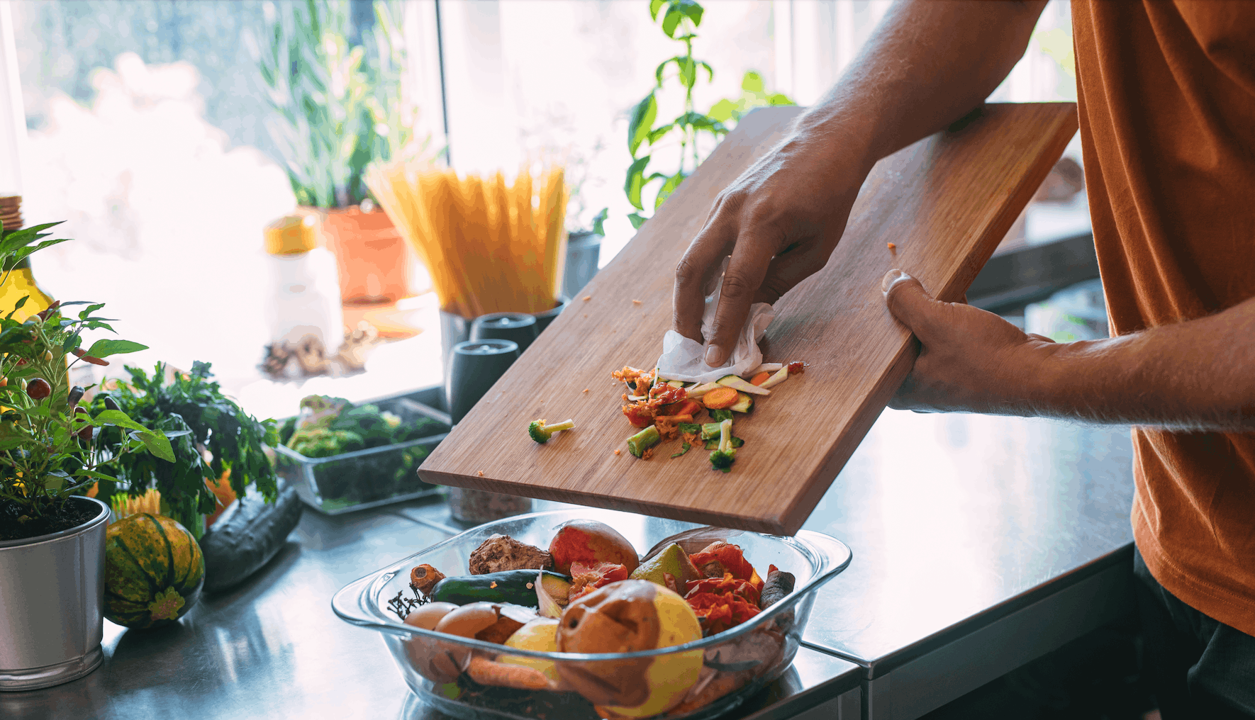 Hands pushing food scraps into bowl on kitchen counter